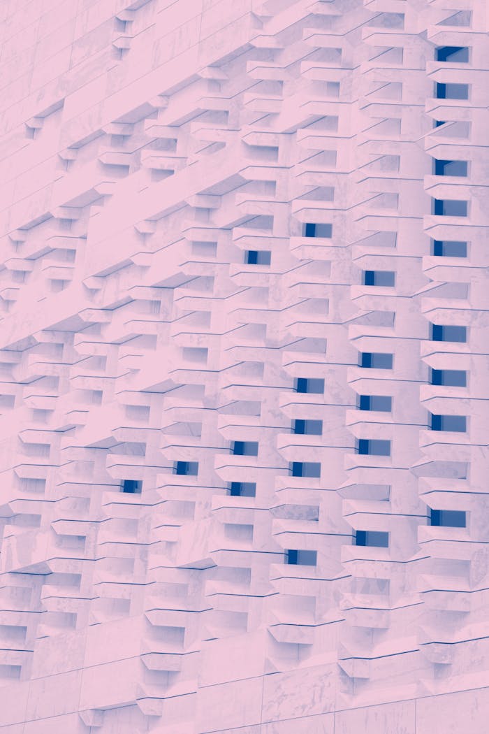 Abstract pink-toned facade with geometric shapes and repetitive patterns.